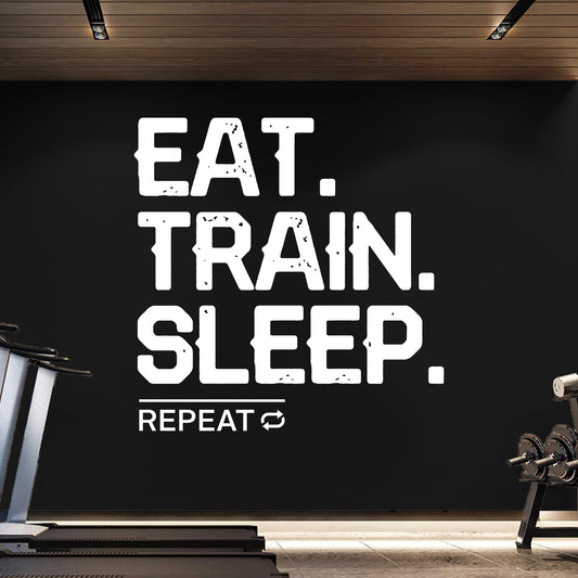 Motivational quote 'EAT. TRAIN. SLEEP. REPEAT' on a black wall in a gym setting.