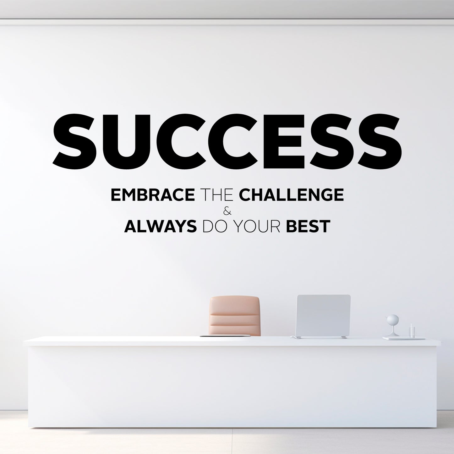 Motivational quote on a white wall with a minimalistic desk setup.