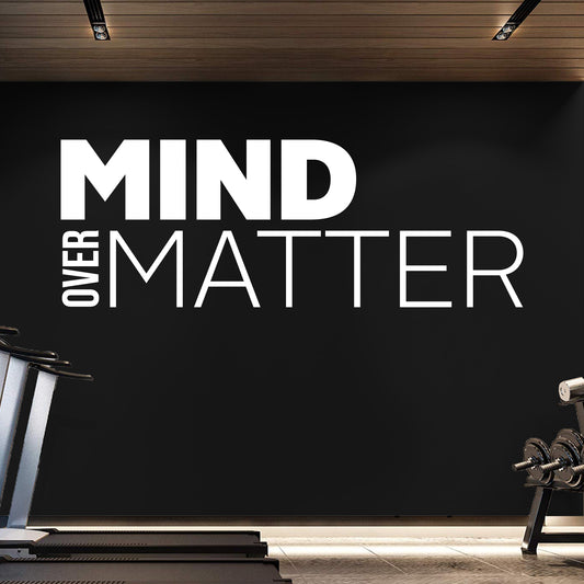 Gym interior with 'Mind Over Matter' motivational quote on a black wall.