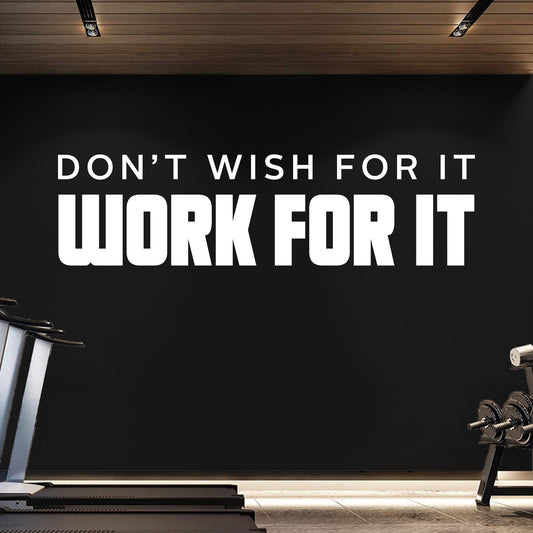Motivational quote on a black wall in a gym setting with exercise equipment.