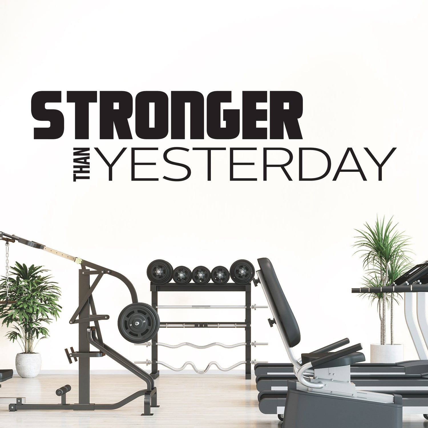 Gym equipment with 'Stronger Than Yesterday' motivational quote on a white wall.