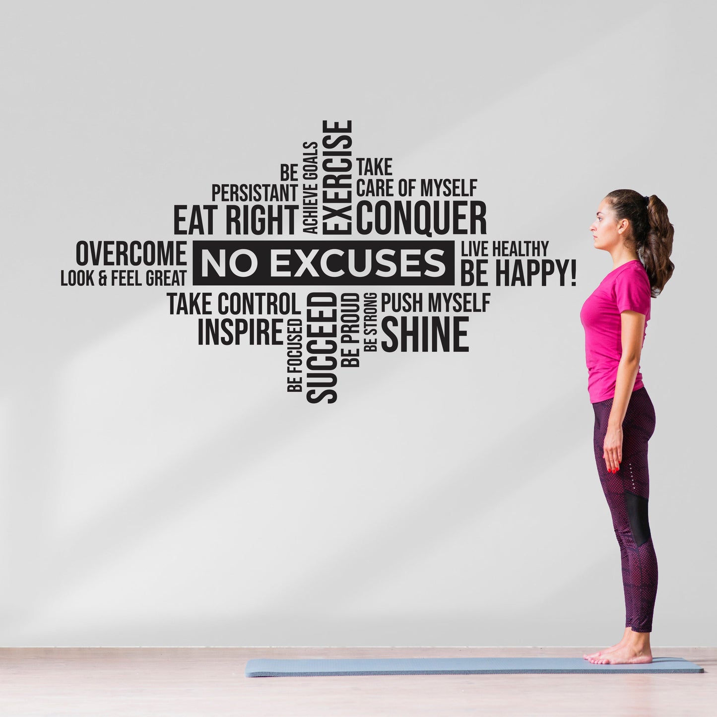 Woman on a yoga mat with motivational wall decal behind her
