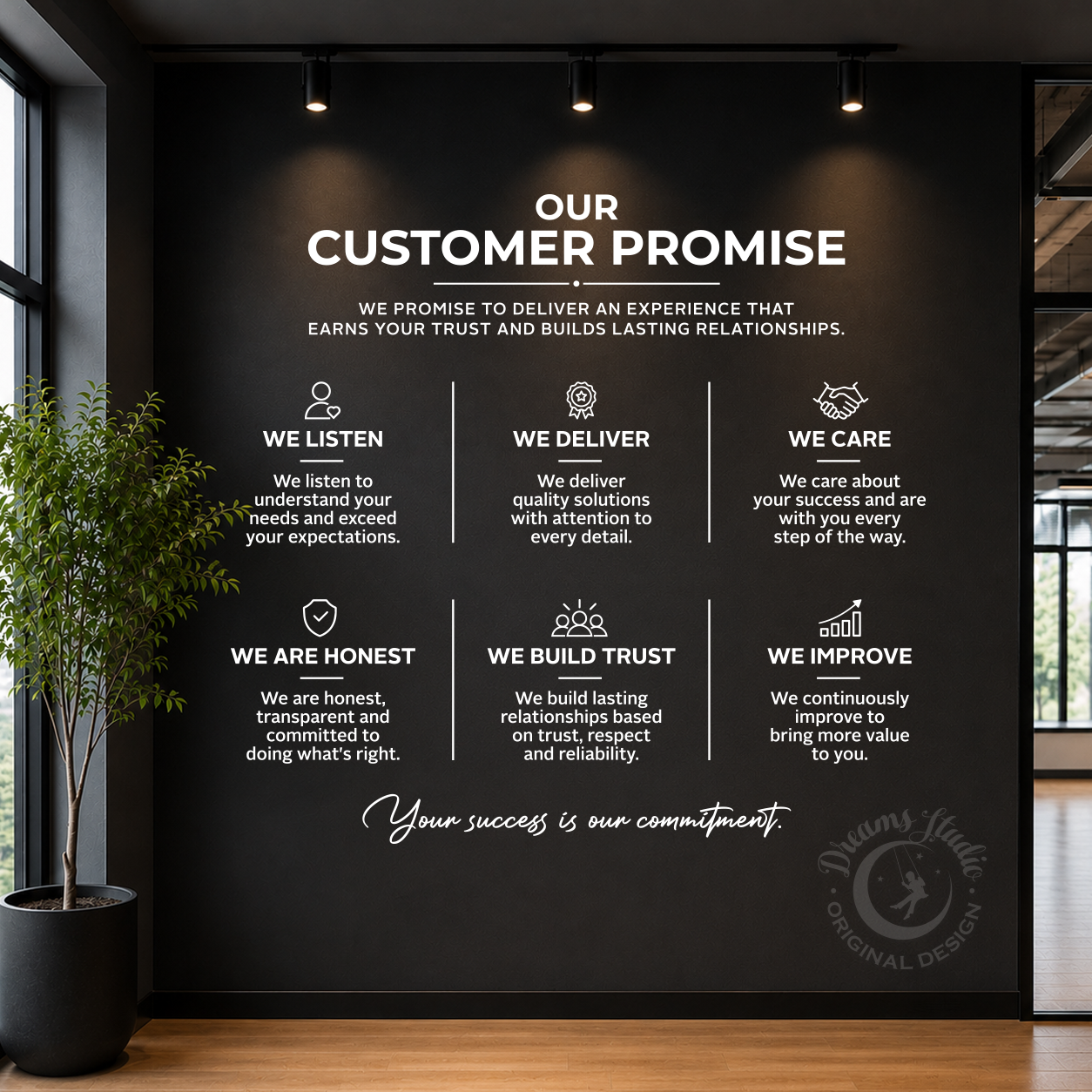 A large black wall in a modern office space displays a white printed 'Our Customer Promise' poster with six key service commitments: Listen, Deliver, Care, Honest, Build Trust, and Improve. The wall is lit by overhead spotlights, flanked by a potted plant on the left and a window on the right.