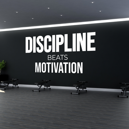 Gym interior with motivational quote 'Discipline Beats Motivation' on a wall.